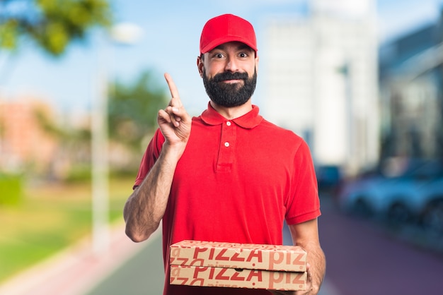 Pizza delivery man pointing up on unfocused background