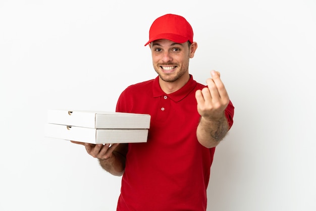 Pizza delivery man with work uniform picking up pizza boxes over isolated  white wall making money gesture