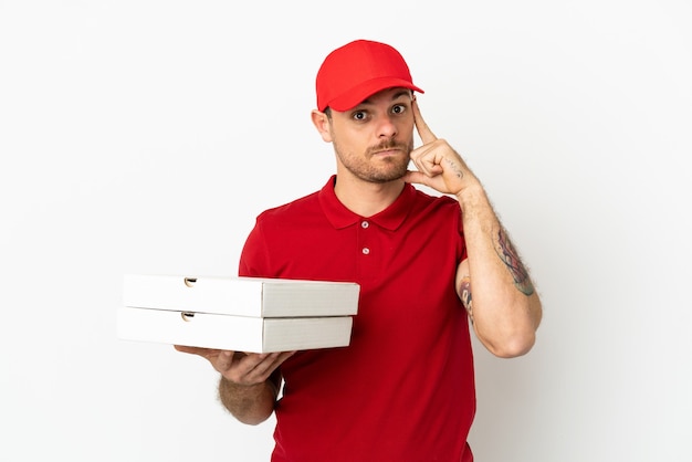 Pizza delivery man with work uniform picking up pizza boxes over isolated  white wall thinking an idea