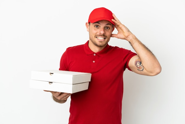 Pizza delivery man with work uniform picking up pizza boxes over isolated  white wall with surprise expression