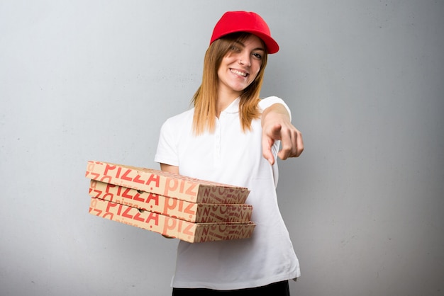 Pizza delivery woman pointing to the front on textured background