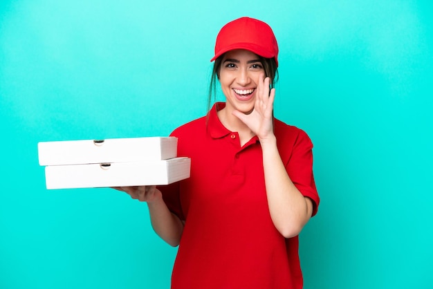 Pizza delivery woman with work uniform picking up pizza boxes isolated on blue background shouting with mouth wide open