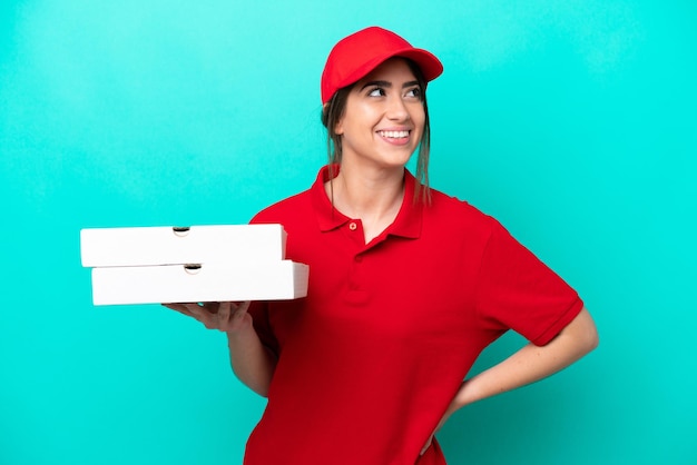 Pizza delivery woman with work uniform picking up pizza boxes isolated on blue background thinking an idea while looking up