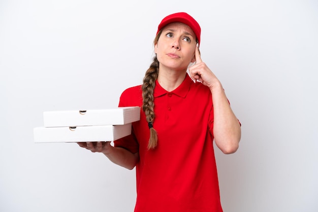 Pizza delivery woman with work uniform picking up pizza boxes isolated on white background having doubts and thinking