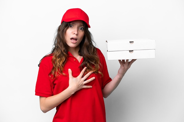 Pizza delivery woman with work uniform picking up pizza boxes isolated on white background surprised and shocked while looking right