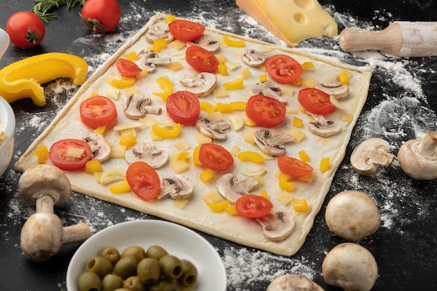 Pizza dough with tomatoes high angle