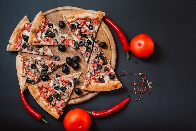 Pizza filled with tomatoes, red pepper, salami and olives