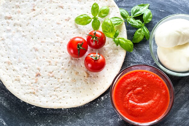 Pizza ingredients on the dark wooden surface