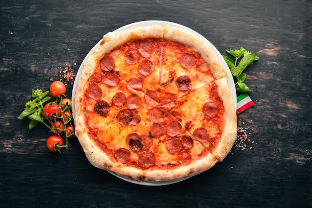 Pizza Margarita with sausages and tomato sauce On a wooden background Top view Free space for your text