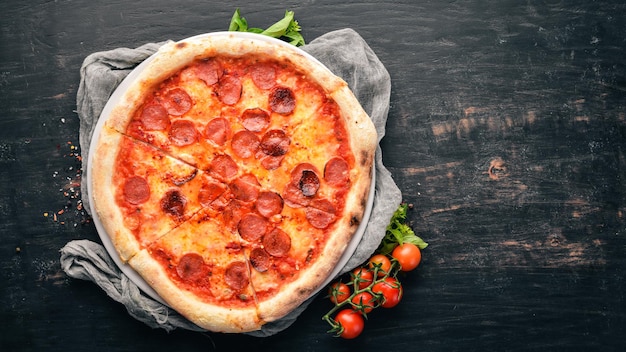 Pizza Margarita with sausages and tomato sauce. On a wooden background. Top view. Free space for your text.