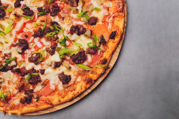 Pizza on paper on a wooden board. Pizza on a black table close-up. Healthy hot food.