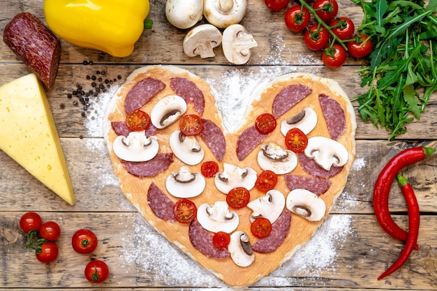 pizza in the shape of a heart and ingredients for Valentine's day, cooking process