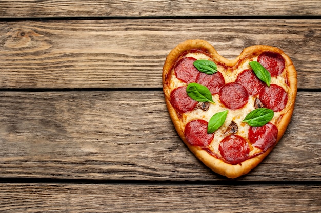 Pizza in the shape of a heart on a wooden table