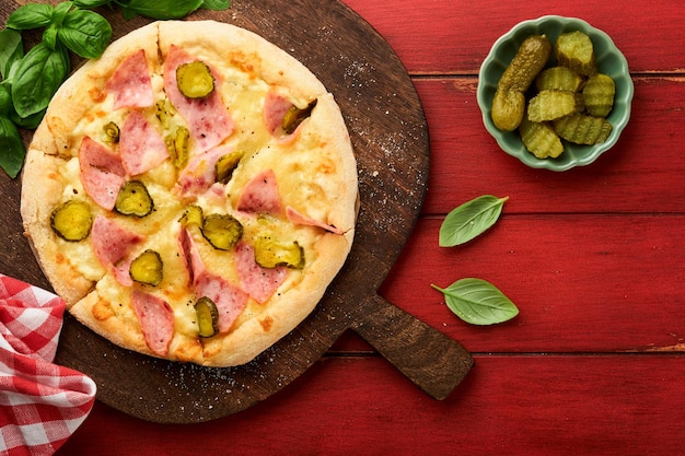 Pizza Traditional Bacon pizza with ham mushrooms pickled cucumber and cheese and cooking ingredients tomatoes basil on wooden table backgrounds Italian Traditional food Top view Mock up