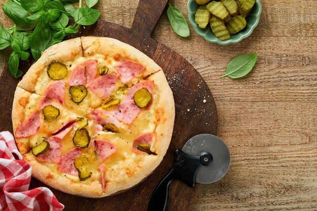 Pizza Traditional Bacon pizza with ham mushrooms pickled cucumber and cheese and cooking ingredients tomatoes basil on wooden table backgrounds Italian Traditional food Top view Mock up