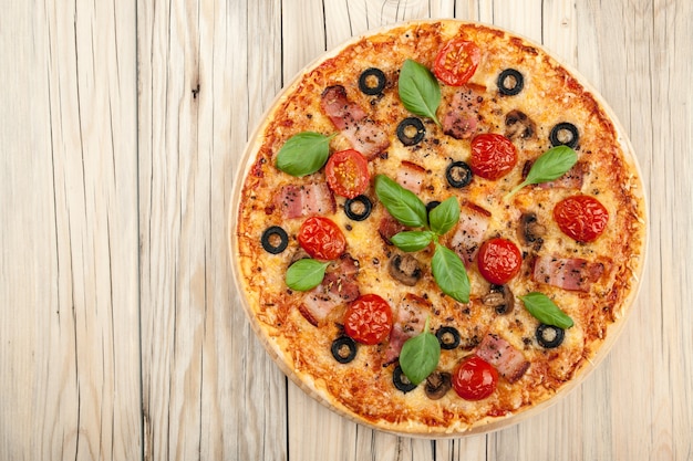 Pizza with bacon and mushrooms on cutting board on wooden background