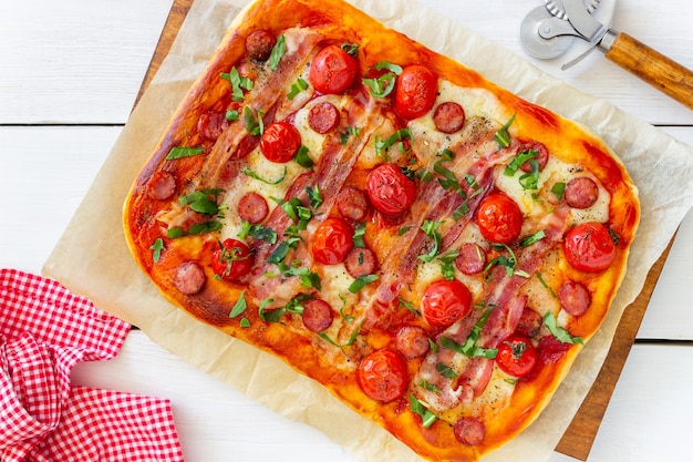 Pizza with bacon, sausage, mozzarella, tomatoes and basil. Italian cuisine. Recipe.