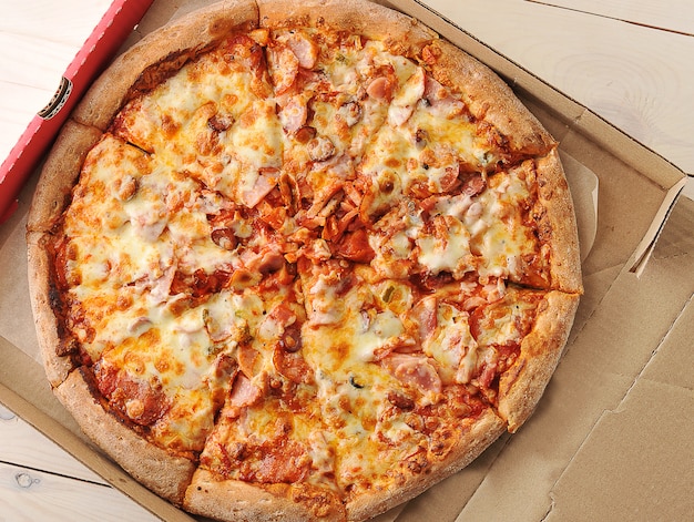 Pizza with cheese and spicy sausages in a cardboard box 