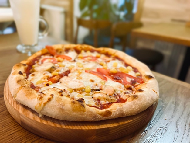 Pizza with chicken tomatoes corn and mozzarella is on the table in a plate Restaurant food selective focus