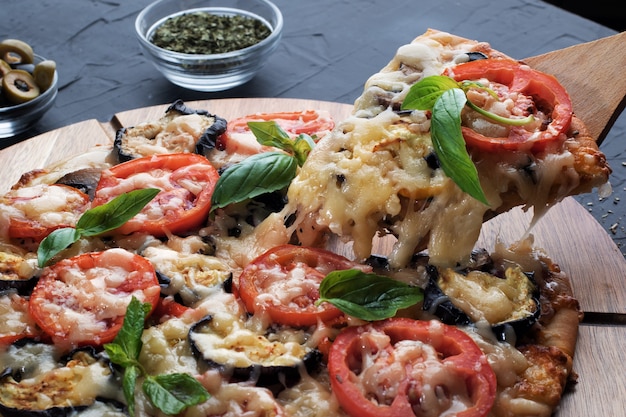 Pizza with eggplant ,olives and mushroom. Italian cuisine. Ingredients for making pizza on a black background.Concept for advertising restaurants or pizzerias.