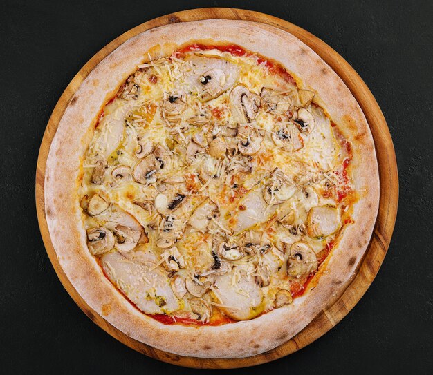 Pizza with ham and mushrooms on a wooden board