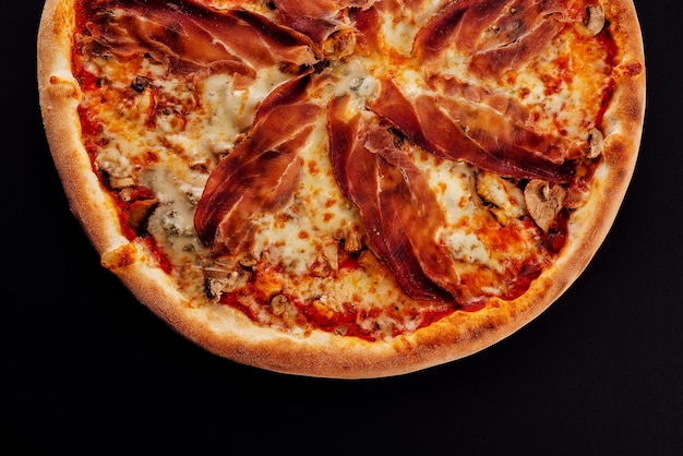 Pizza with jamon cheese and mushrooms on black