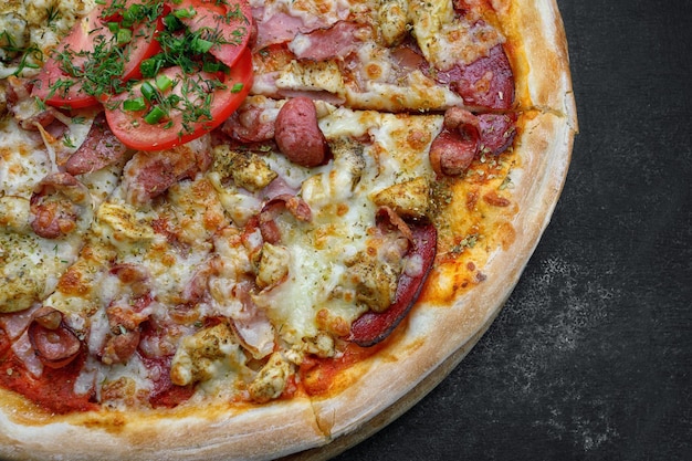 Pizza with meat sausage and chicken cheese and tomatoes on a gray concrete background with selective focus