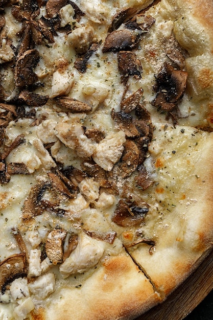 Pizza with mushrooms and chicken on a wooden board vertical