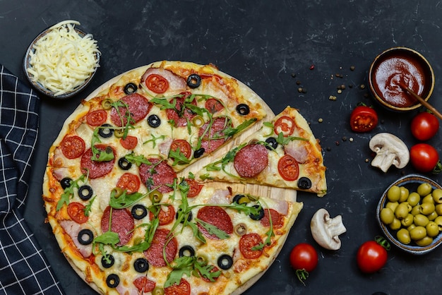 A pizza with olives, mushrooms, and cheese on a black background