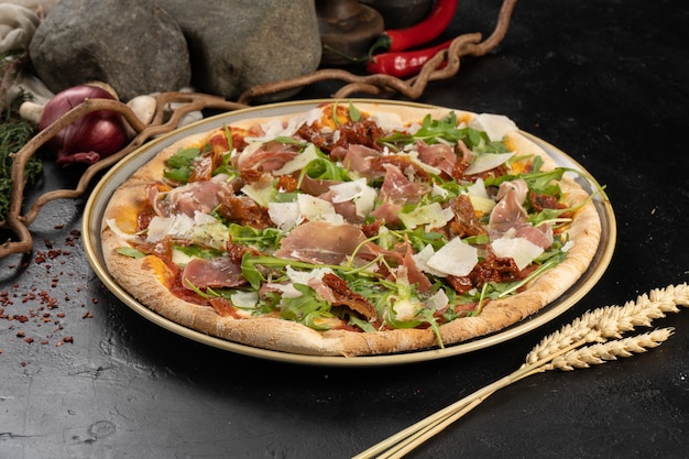 Pizza with Parma ham, parmesan cheese, dried tomatoes and arugula