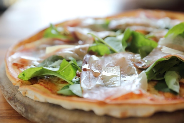 Pizza with parma ham salad rocket on tomato sauce with wood table background