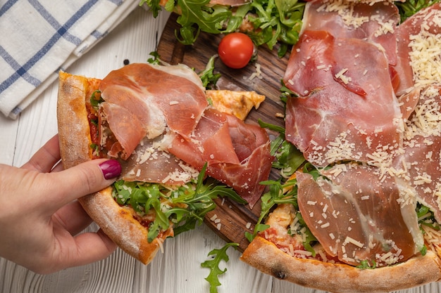 Pizza with prosciutto, arugula, tomatoes and parmesan