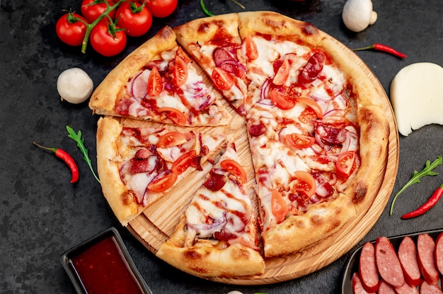 pizza with sausages mushrooms tomatoes and cheese on a stone background