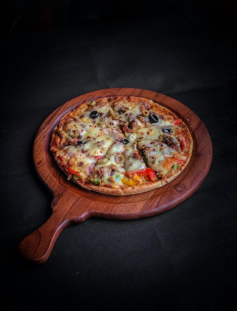 Pizza with tomato cheese capsicum onion on a wooden base