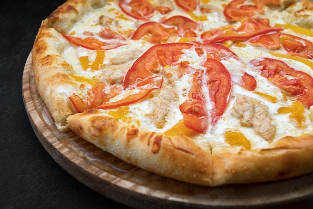 Pizza with vegetables chicken and cheese on a wooden board