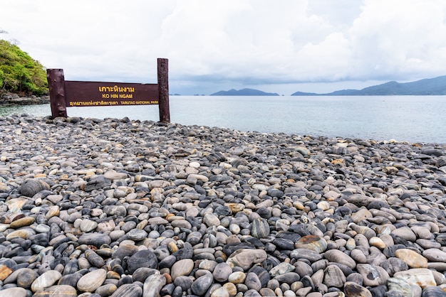 Place name plate of Ko Hin Ngam island and beautiful nature landscape of unusual rock near the sea in summer is a famous tourist attractions of Tarutao National Park, Satun, Thailand