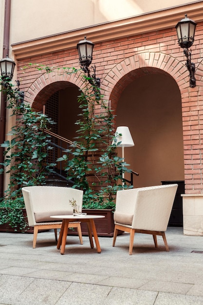 A place to relax with armchairs made ââof straw and torchere in the yard against the background of brick arches