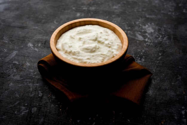 Plain curd or yogurt or Dahi in Hindi, served in a bowl over moody background. Selective focus