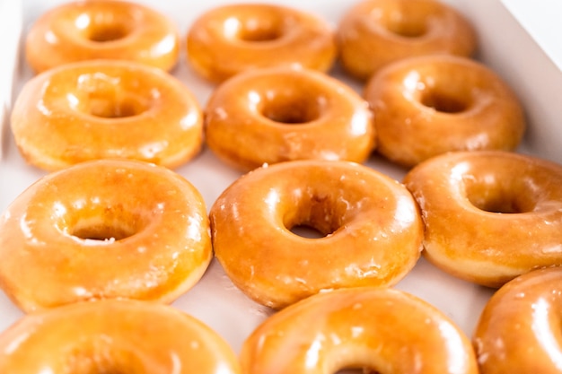 Plain glazed store-bought doughnuts in a white paper box.