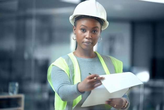 The plan is everything. Cropped portrait of an attractive young female architect looking at blueprints while standing in her office.