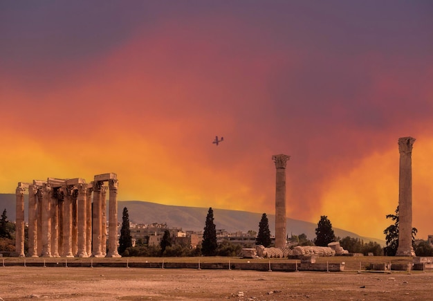 The plane extinguishes a fire on background Antique marble Temple of Olympian Zeus in Athens, Greece