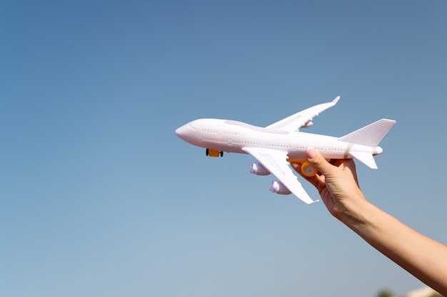 Plane in female hand clear blue sky background copy space. Travel and vacation. Book tickets now. Toy white plane fly vacation destinations. Travel comfortable premium class airlines. Discover world.