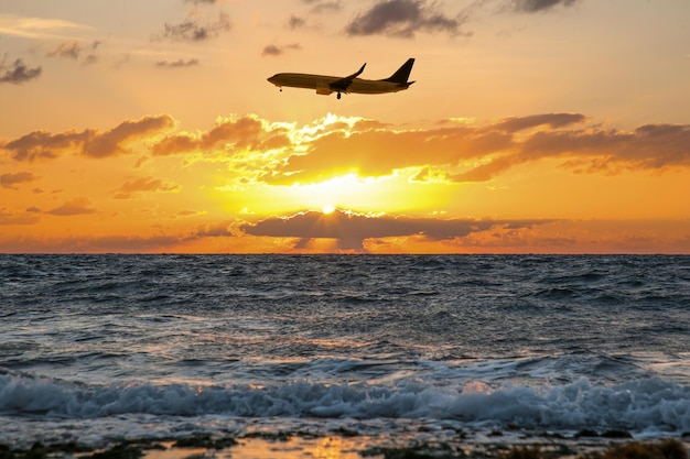 Plane flying over sea during sunset Sun shining through clouds