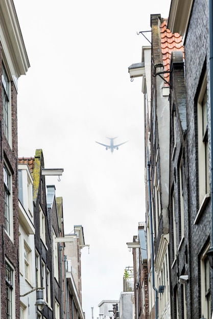 The plane in the fog flies over tall houses in the city Selective focus Vertical