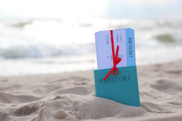 Plane tickets and passport on the beach near the sea close up