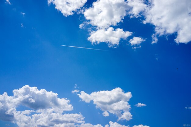 Plane trail in clear sky with clouds