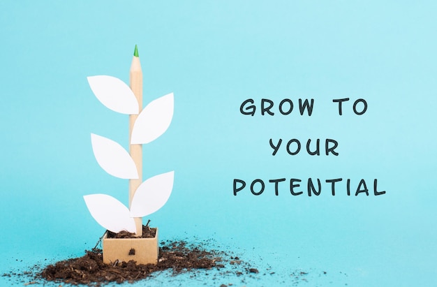 Plant made from a pencil and paper, the phrase grow to your potential is standing on the background