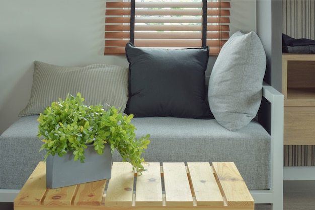 Plant pot on center wooden table and comfy seat in living room