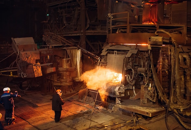 Plant for the production of steel. An electric melting furnace. Factory worker takes a sample for metal.