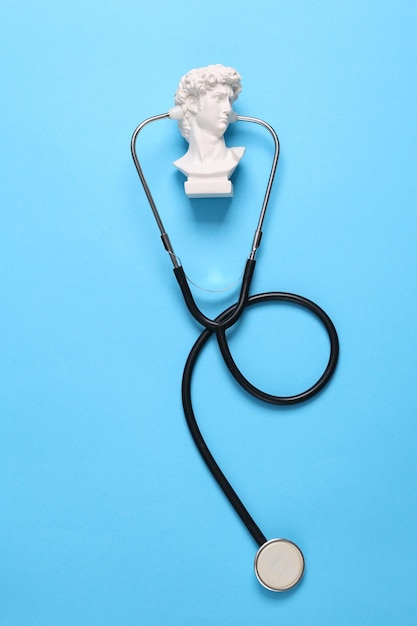 Plaster bust of David with a stethoscope on a blue background Medical concept